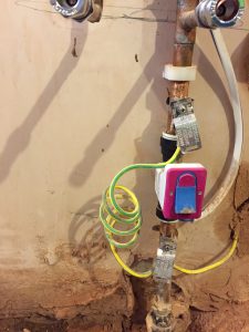 A picture showing piping protruding from a wall with connecting green and yellow wiring
