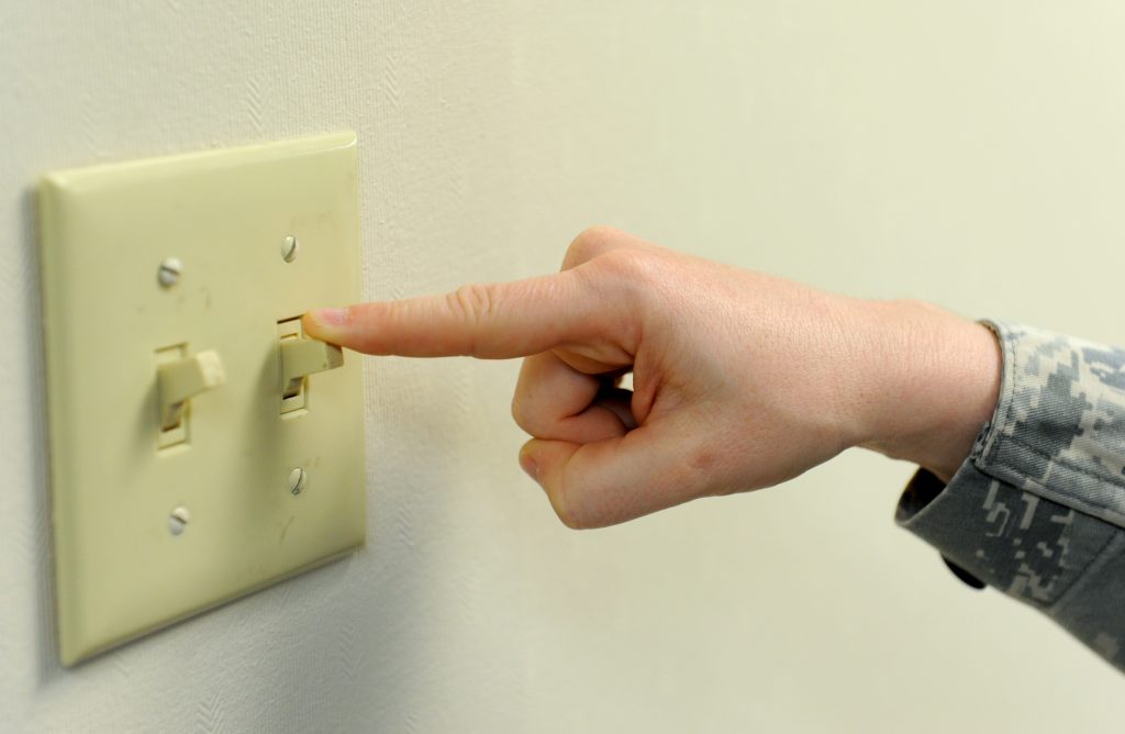 An image of someone carrying out electrical checks by flicking a light switch