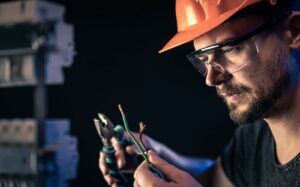 Electrician inspecting damaged electrical wiring during fault diagnosis