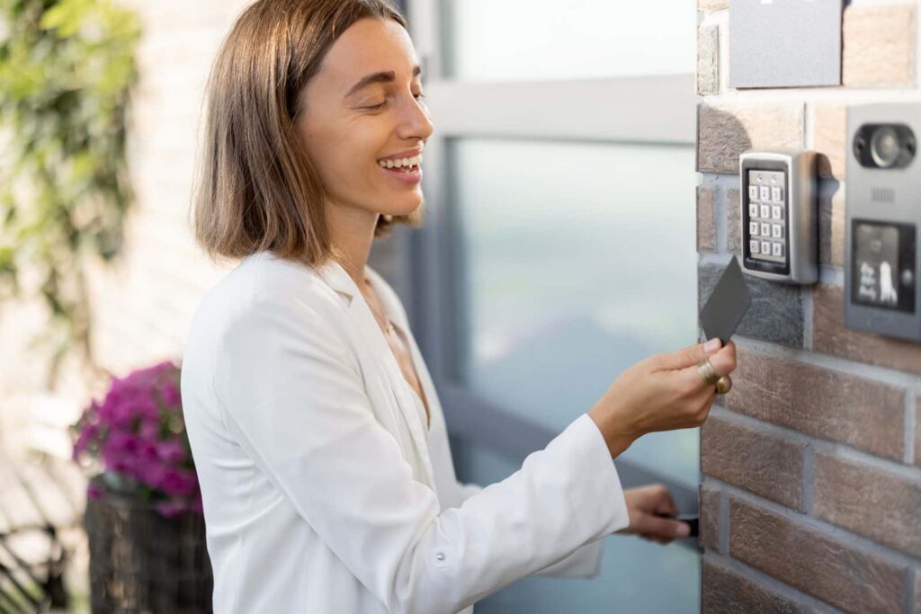 Woman using an access card beside an intercom and keypad entry system