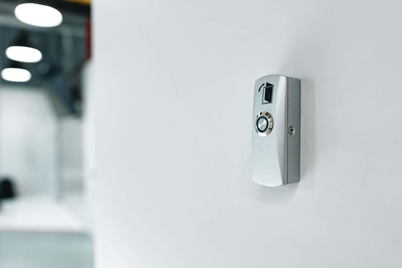 Wall-mounted door-release button used with an intercom access system